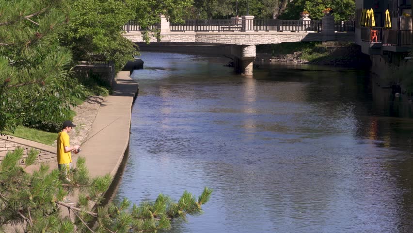 Man Catches a Small Fish in City Stream and Throws It Back