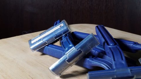 Generic blue razors shavers in a pile isolated indoors on wooden table