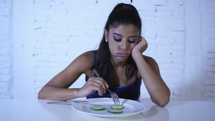 Portrait o f young attractive woman feeling sad and bored with diet not wanting to eat vegetables or healthy food in Dieting Eating Disorders and weight loss concept. | Shutterstock HD Video #1017599440