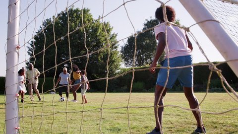 Multi generation black family playing football in garden