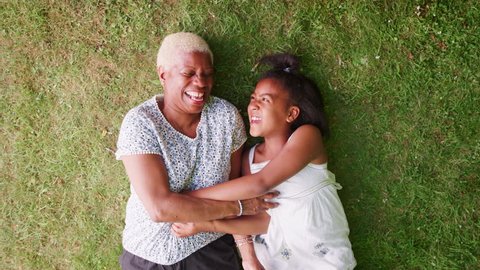 Black girl and grandmother lying on grass, overhead close up