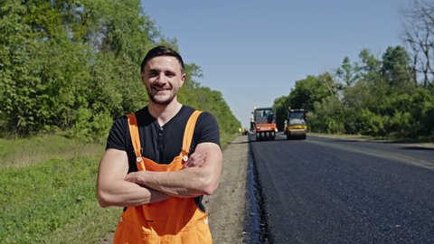 Man in overalls standing alongside a tarred road