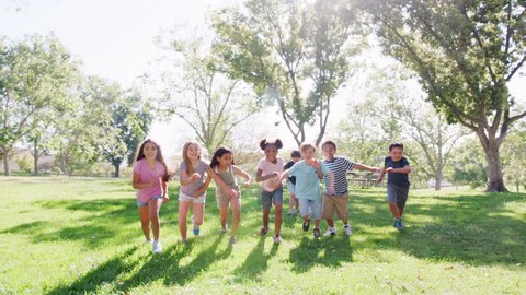 Group Of Children With Friends In Park Running Towards Camera Shot In Slow Motion