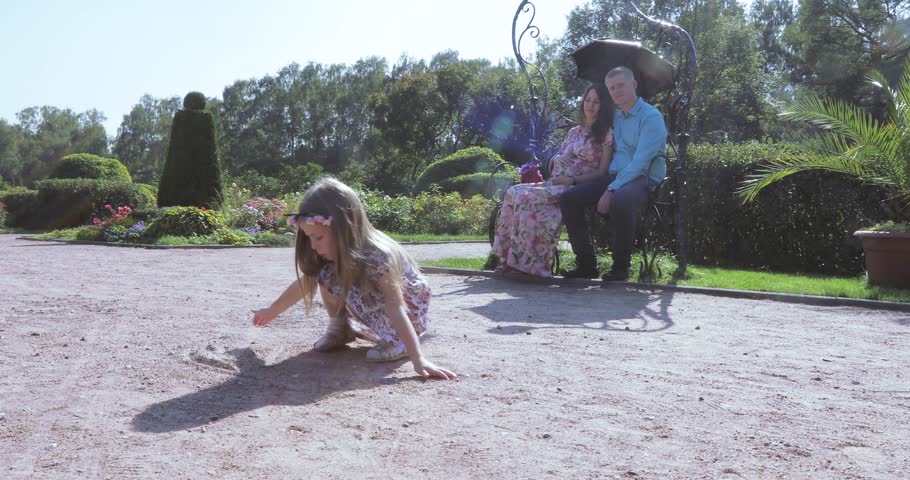 In the city park a child girl draws on the sand
