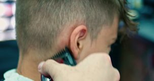 Barber shave head of boy with electric razor closeup shot