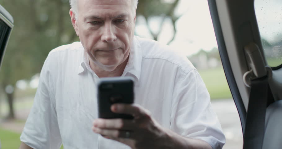 A mature man with a mobile phone checks the ride sharing app and verifies with the driver then contentedly gets into the back seat and engages in casual conversation. Royalty-Free Stock Footage #1017621664