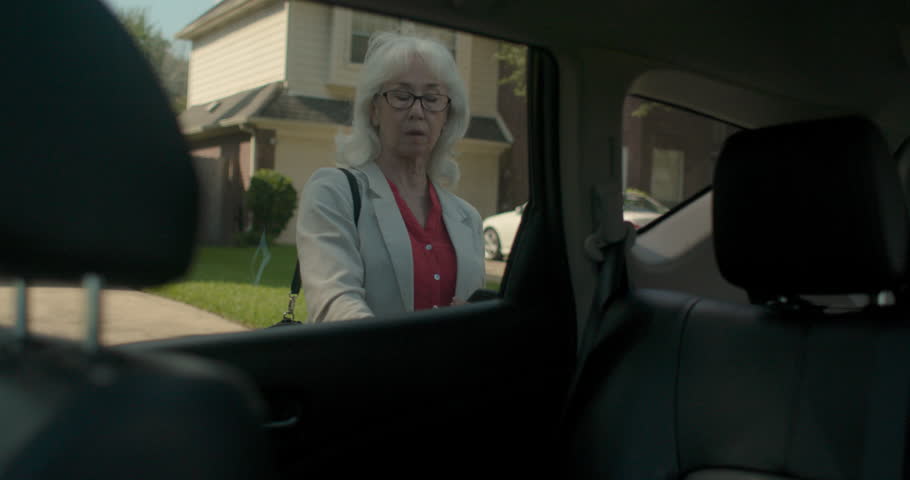A tech savvy senior adult using an app on her mobile phone greets and engages in conversation with the ridesharing driver off camera as she settles in to the backseat and puts on her seat belt Royalty-Free Stock Footage #1017621730