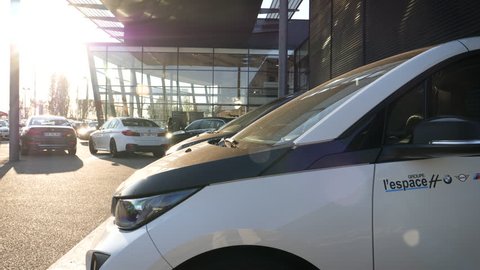 PARIS; FRANCE - CIRCA 2018: Cinematic view over woman admiring the new electric vehicle from BMW i1 i3 and i3S admiring the futuristic body of the luxury high-roof hatchback car