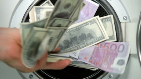 man puts money in the washing machine, dollars and euros, closeup