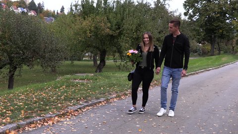 Young guy with a girl walk in the park, holding hands