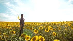 man farmer exploring the field with sunflowers. slow motion video. Man lifestyle farmer hand hold bottle of sunflower oil the field at sunset. man farmer agriculture plastic bottle oil sunflower