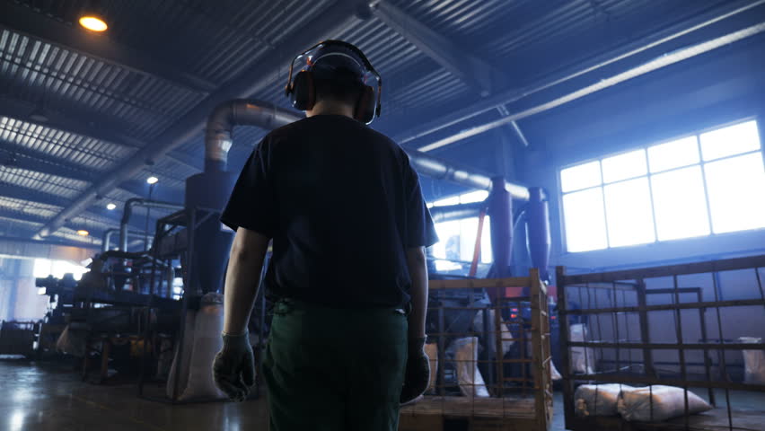 KAZAN, TATARSTAN/RUSSIA - AUGUST 24 2018: skilled technician in blue uniform and earphones walks along lorries repairing workshop with automated equipment on August 24 in Kazan | Shutterstock HD Video #1017643303