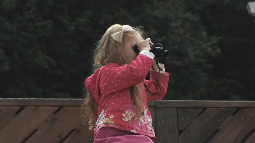 Little beautiful girl looking through binoculars on the beach 4k