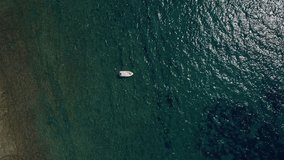 A wide Aerial shot flying around the boat where a young woman is relaxing and sunbathing in the middle of the Mediterranean water. Top travel destination. Vacation in Croatia.