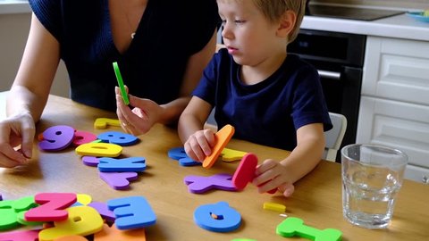 Mother with preschool boy learning english alphabet and numbers