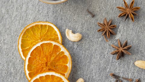 christmas and seasonal drinks concept - hot mulled wine, orange slices, cookies and aromatic spices on grey background