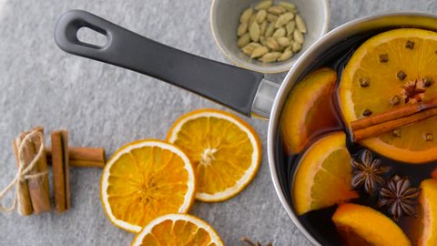 christmas and seasonal drinks concept - pot with hot mulled wine, orange slices and aromatic spices on grey background