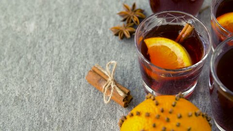 christmas and seasonal drinks concept - glasses of hot mulled wine with orange slices and aromatic spices on grey background
