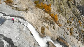 Aerial view of girl backpacker hiking, enjoying beautifull epic waterfall in Caucasus Mountains, Svaneti, Georgia. Georgia Travel concept - hiking trail. Trekking Discover concept drone video 4K.