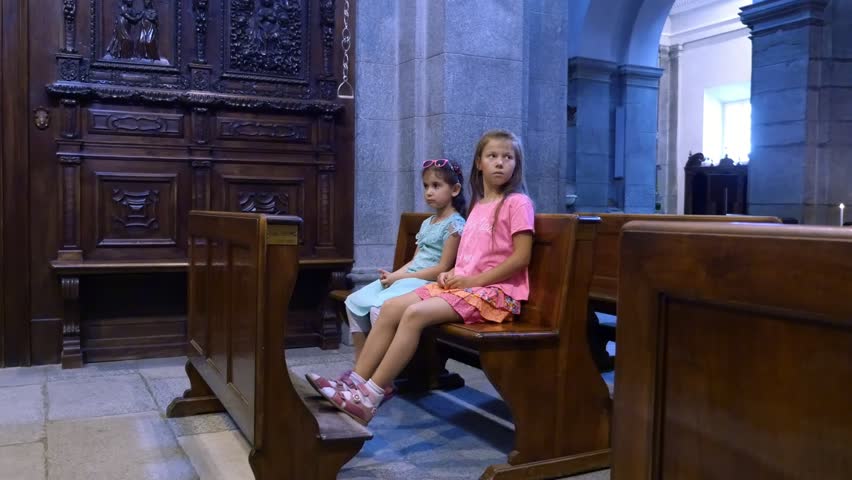 OROPA, BIELLA, ITALY - JULY 7, 2018: children are sitting on a bench in a catholic old church, looking at wall paintings. Shrine of Oropa, Sanctuary, in the mountains near the city of Biella, Piedmont | Shutterstock HD Video #1017669532