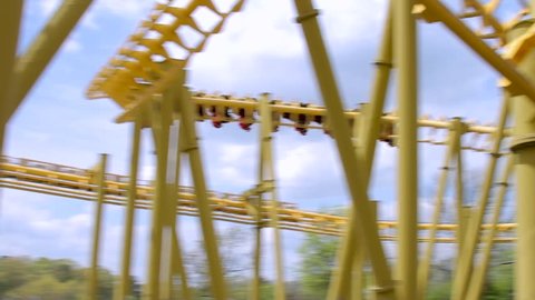 Close up of fast moving inverted roller coaster moving through cork screw.