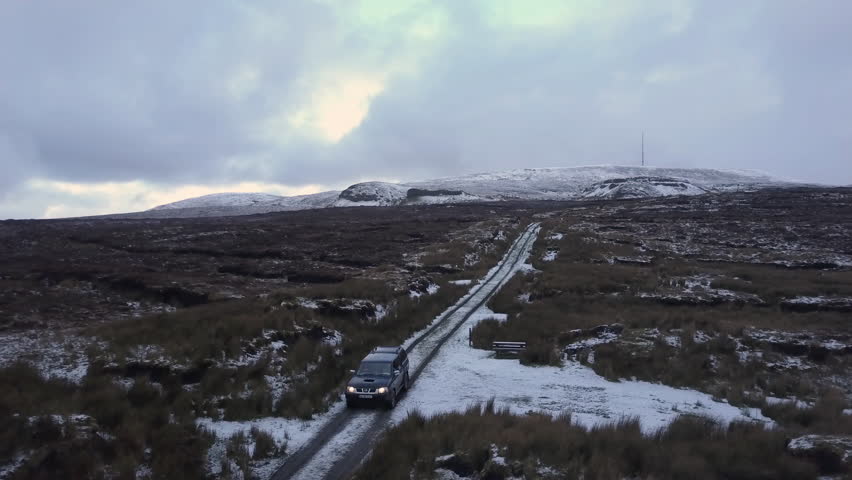 A jeep drives over a frosty mountain in winter Dark and Moody 4K