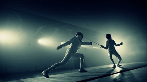Footage of two fencing athletes duel . Two Professional Fencers Show Masterful Swordsmanship in their Foil Fight. Fencing training . Shot on ARRI ALEXA camera . 