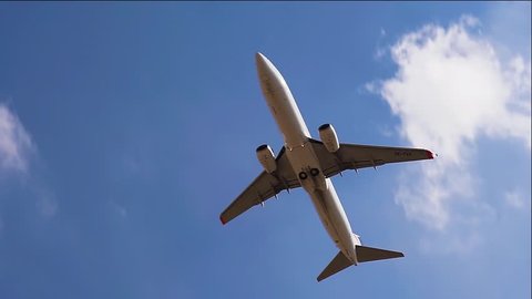 Plane flying over head on blue sky. Airplane takeoff into the sky. Slow motion.