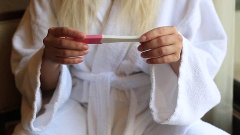 Female hands holding pregnancy test, turning to show two lines, family planning