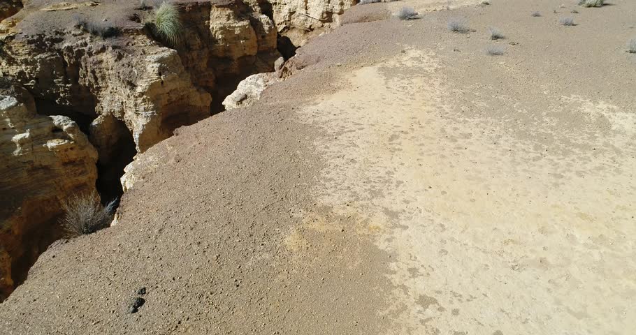 Aerial drone scene of Ocre Canyon in Famatina Mountains and Yellow river. Camera moves backwards ascending above golden sandstone, with cliffs, layers, gullies, eroded landscape. La rioja, Argentina