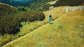 Aerial View Running woman. Runner is jogging in summer sunny day around trees and mountains background under sun light with blue sky, Drone 4K Video Aerial View