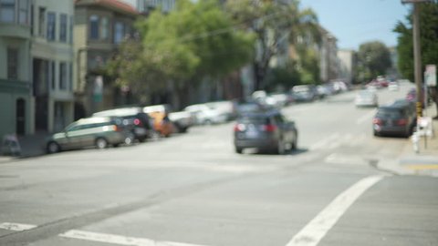 Exterior scene of intersection in San Francisco suburb with apartment buildings. Blurred background of cars driving uphill. 4k