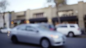 Defocused street view of San Francisco cars driving through district with shop fronts. Public transportation bus carries passengers through the city. 4k