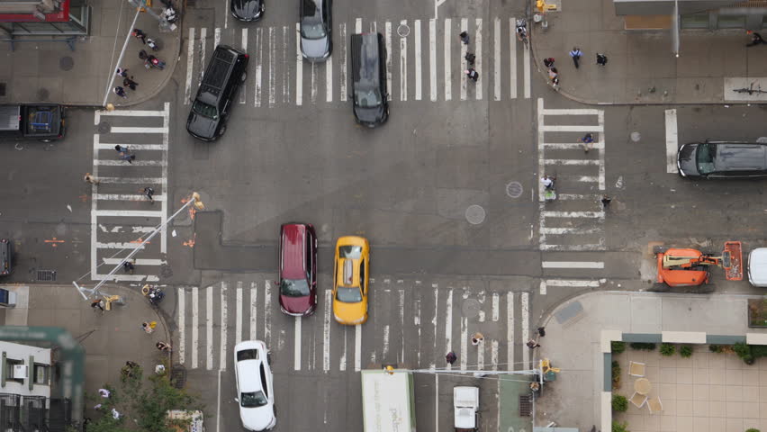 A top down bird's eye view of a typical Manhattan intersection as traffic and pedestrians travel on the streets below.  	 Royalty-Free Stock Footage #1017688309