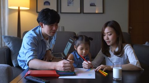 4k video of father and mother teach their daughter doing her homework at home  స్టాక్ వీడియో