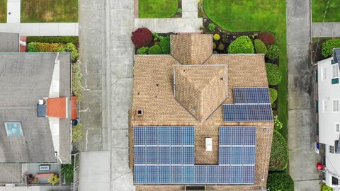 Aerial view of a suburban home rooftop with solar panels; direct view down rising in altitude