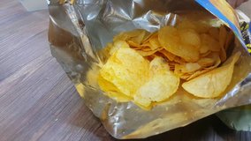 Footage of hand pick potato chips from pack to eat