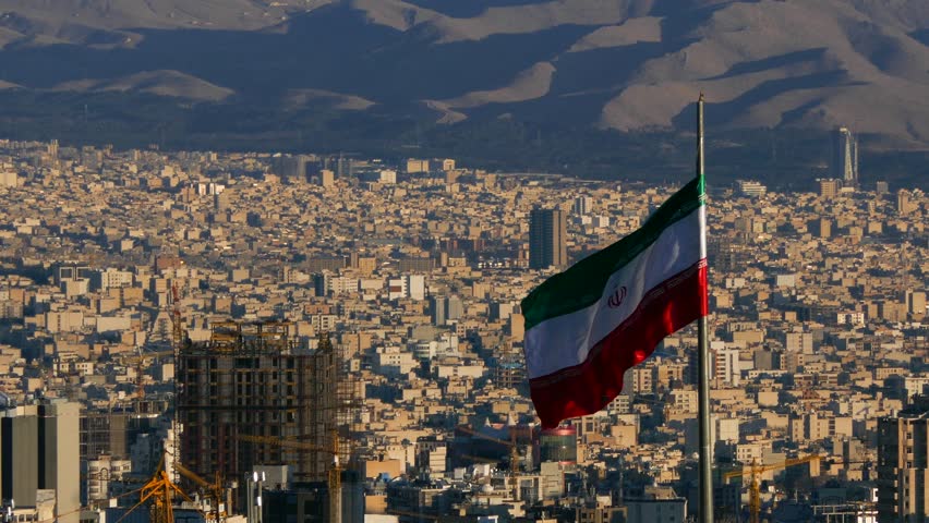 Iranian flag waving in the middle of the capital city of Tehran in a sunny day Royalty-Free Stock Footage #1017725236