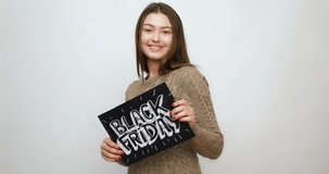 sale, shopping and people concept - Young smiling brunette girl is holding a black friday sign. Black Friday sale. Black Friday sale promotion video