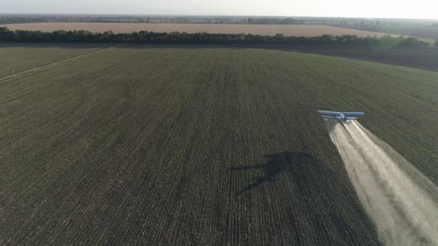 beautiful view of vintage airplane in Solar Beams flies over green Grain field and splashing chemicals against parasite into agriculture in aerial view