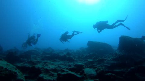 Silhouette view of scuba divers swimming over reef in Kas, Turkey