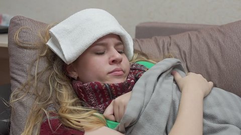 A teenage girl is covered with a blanket, her fever, headache, flu.