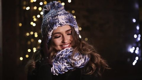 Beautiful smiling brunette in a winter hat in the night city.