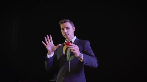 Magician shows focus on the stage. Trick with red fabric and flower.