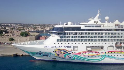 Rodos, Greece - September 24, 2018: Aerial footage of the Norwegian Spirit cruise ship docked at the old town port and a general view of the old city and bay.
