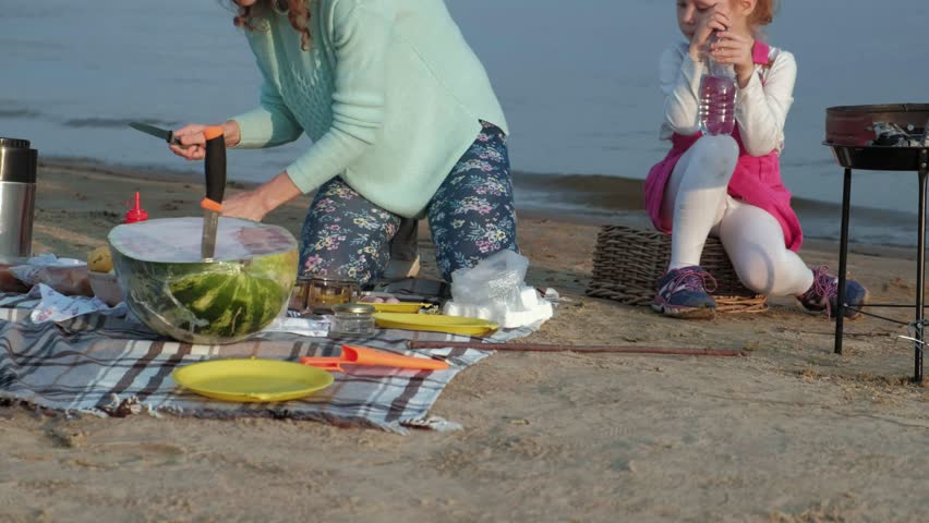 Mother and daughter fry meat and vegetables on a barbecue on the beach on the beach 4k