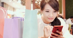 woman use phone happily with her shopping bag in the restaurant