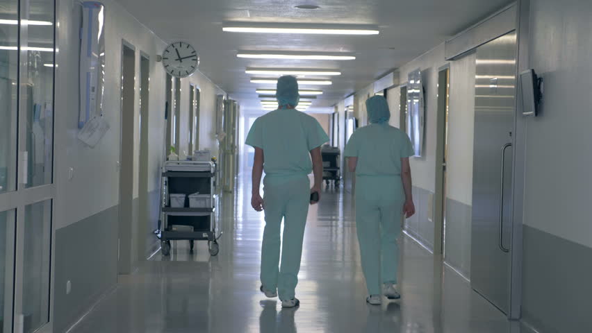 People in a clinic building. Man and woman walking through an empty hallway in hospital. | Shutterstock HD Video #1017757147