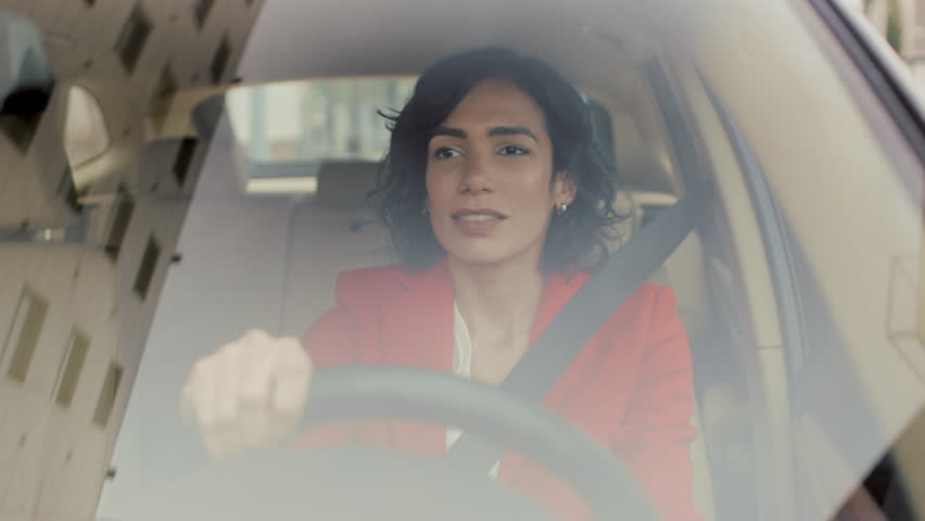 Portrait of beautiful Young Woman Driving Car through big Sunny City. Camera Shot Made From the Front Windshield. Royalty-Free Stock Footage #1017759634