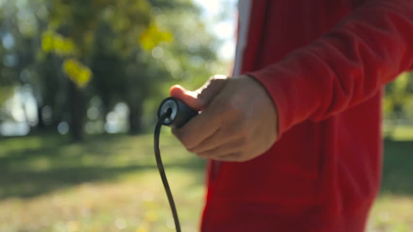 Adult man excercising with jumping rope. Focus on the hand.